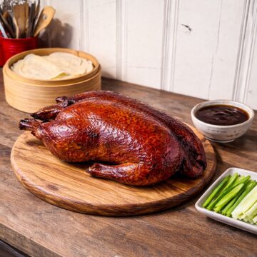 peking duck on a wood tray with spring pancakes, cucumbers and scallions