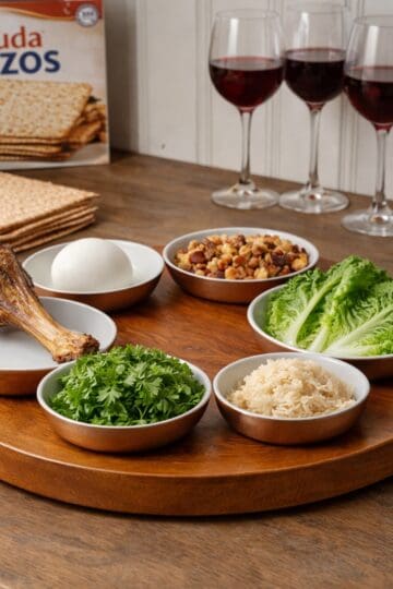 traditional sader plate on a wood conunter, matzh and wine glasses in the background